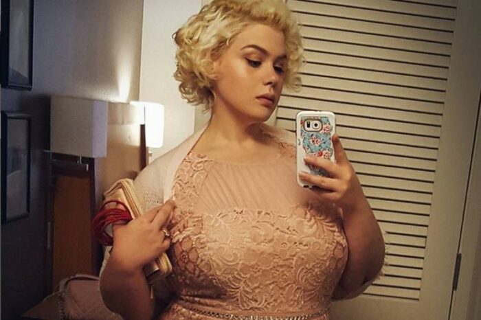 Amber poses in a dress with short, blonde hair than is curled in the style of Marilyn Monroe.